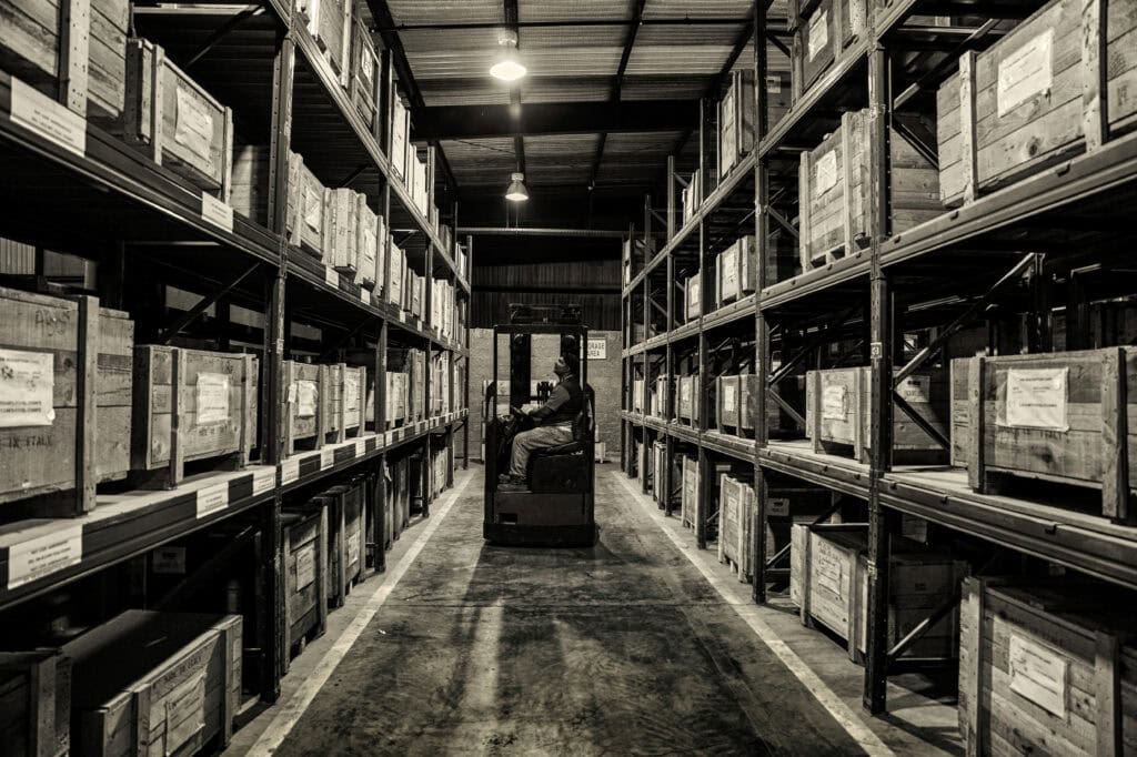 Forklift operator arranging inventory in warehouse storage racks.