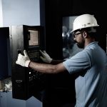 Industrial control panel operator working on automated machinery at a manufacturing facility.