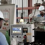 High-precision industrial testing technicians performing IVM testing on machinery in a factory setting.